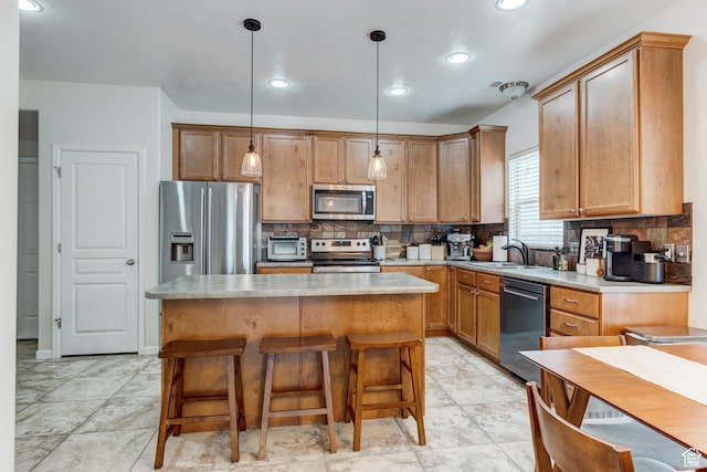 kitchen featuring appliances with stainless steel finishes, a sink, backsplash, and a kitchen island