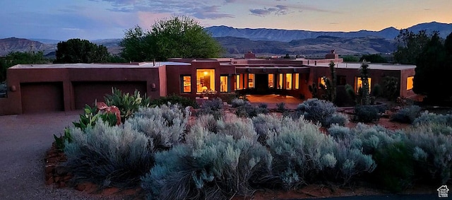 1657 N Kayenta Dr, Ivins, UT 84738 - back of house at dusk with an attached garage, a mountain view, and stucco siding