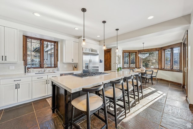 9255 Par Ct, Park City, UT 84098 - kitchen featuring a sink, stone tile flooring, light countertops, stainless steel appliances, and a kitchen bar