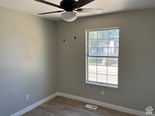 unfurnished room featuring baseboards, a textured ceiling, visible vents, and dark wood-type flooring