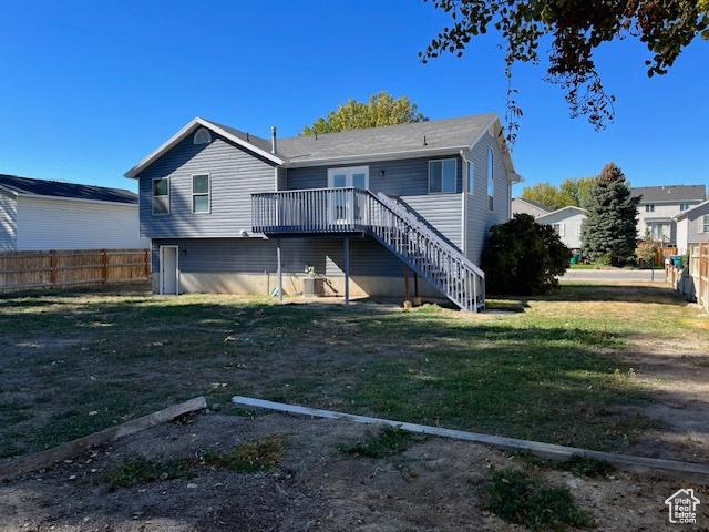 rear view of house featuring fence, stairway, a deck, and a yard
