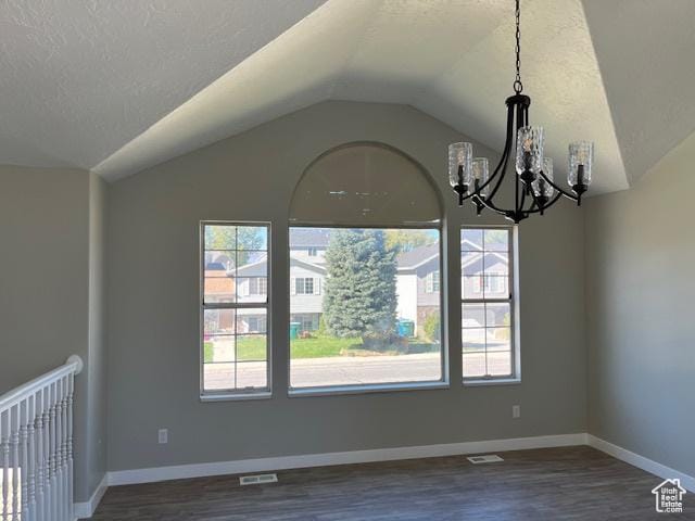 unfurnished dining area featuring a textured ceiling, dark wood-type flooring, visible vents, baseboards, and vaulted ceiling