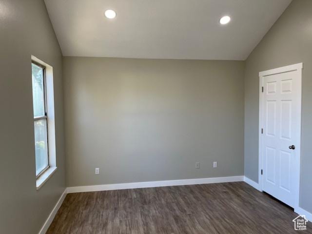 spare room featuring lofted ceiling, recessed lighting, dark wood-style floors, and baseboards