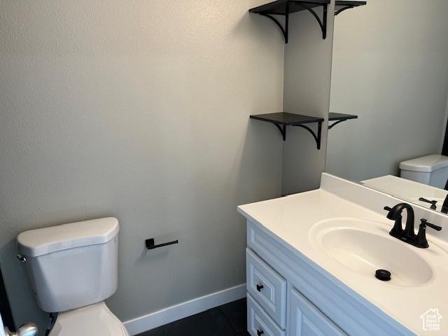 half bath featuring baseboards, vanity, and toilet