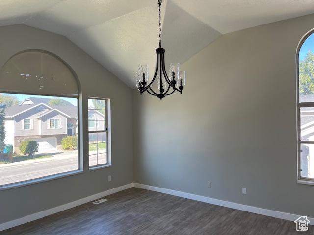 unfurnished room with visible vents, an inviting chandelier, dark wood-type flooring, vaulted ceiling, and baseboards