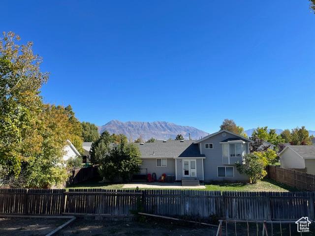 back of property featuring entry steps, a fenced front yard, and a mountain view