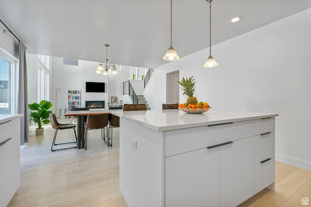 134 N Eden Brook Way, Saratoga Springs, UT 84045 - kitchen with a warm lit fireplace, light countertops, modern cabinets, and light wood-style flooring