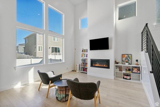 134 N Eden Brook Way, Saratoga Springs, UT 84045 - living area featuring a towering ceiling, baseboards, wood finished floors, and a glass covered fireplace