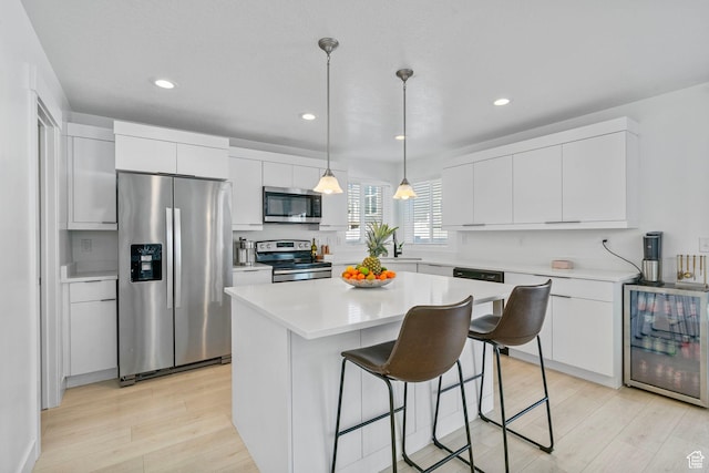 134 N Eden Brook Way, Saratoga Springs, UT 84045 - kitchen with beverage cooler, stainless steel appliances, a breakfast bar, white cabinetry, and light countertops