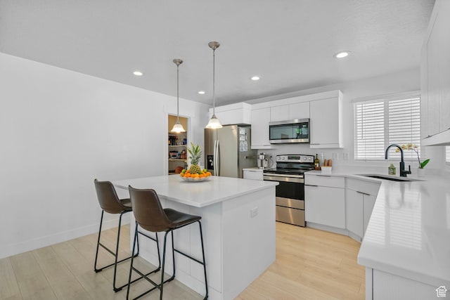 134 N Eden Brook Way, Saratoga Springs, UT 84045 - kitchen featuring a kitchen island, a sink, appliances with stainless steel finishes, light wood finished floors, and a kitchen bar