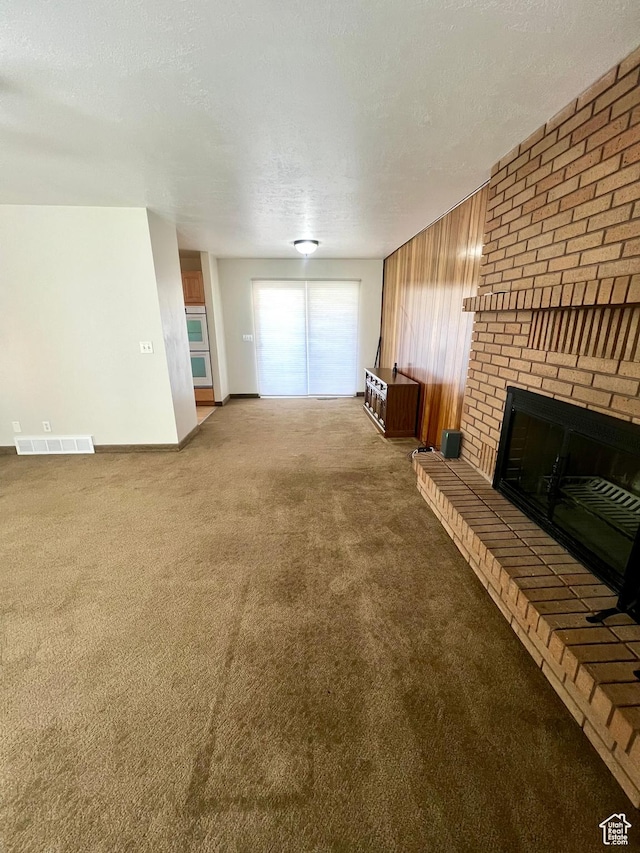 305 N 200 E, Elsinore, UT 84724 - unfurnished living room featuring visible vents, a brick fireplace, carpet flooring, wood walls, and a textured ceiling