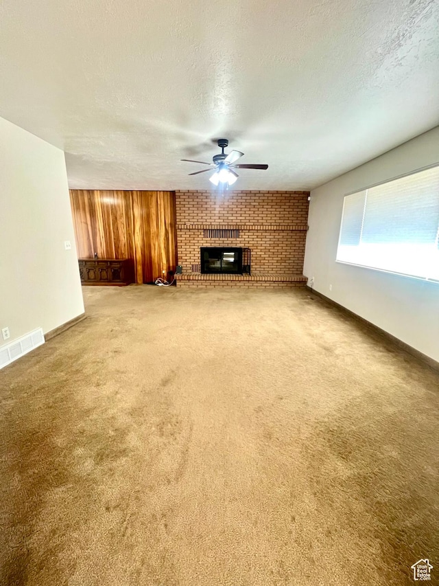 305 N 200 E, Elsinore, UT 84724 - unfurnished living room with visible vents, a ceiling fan, carpet, wood walls, and a fireplace