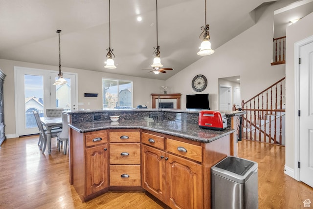 990 W Adams Cir, Bluffdale, UT 84065 - kitchen featuring light wood-style floors, brown cabinetry, vaulted ceiling, and hanging light fixtures