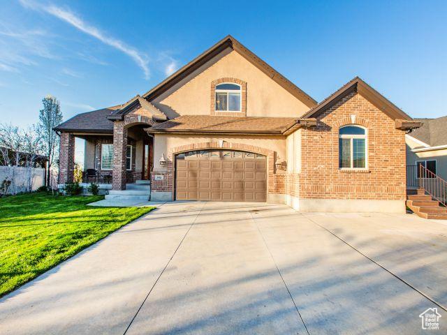 990 W Adams Cir, Bluffdale, UT 84065 - view of front of home featuring concrete driveway, a front lawn, brick siding, and stucco siding