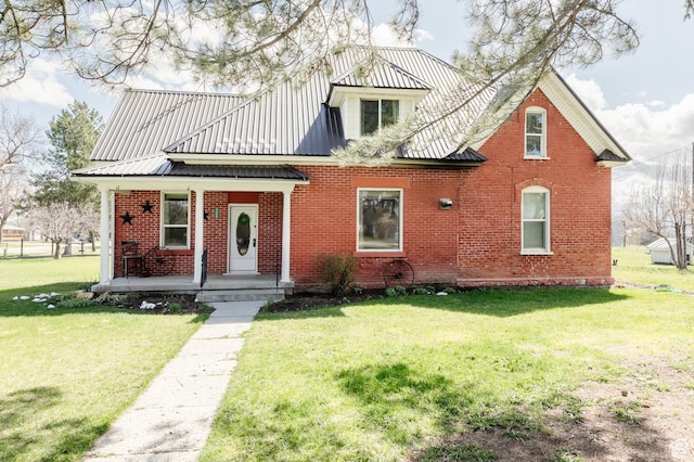 view of front of home featuring covered porch, brick siding, a front yard, and metal roof