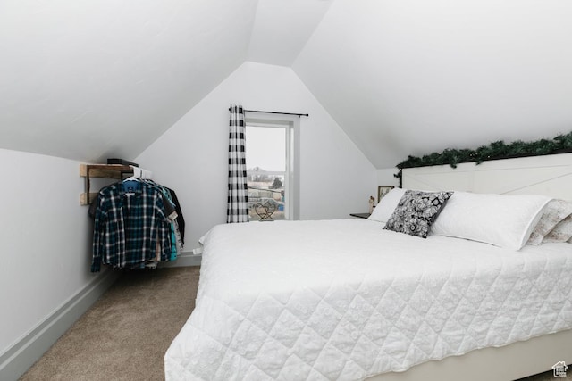 carpeted bedroom with vaulted ceiling and baseboards