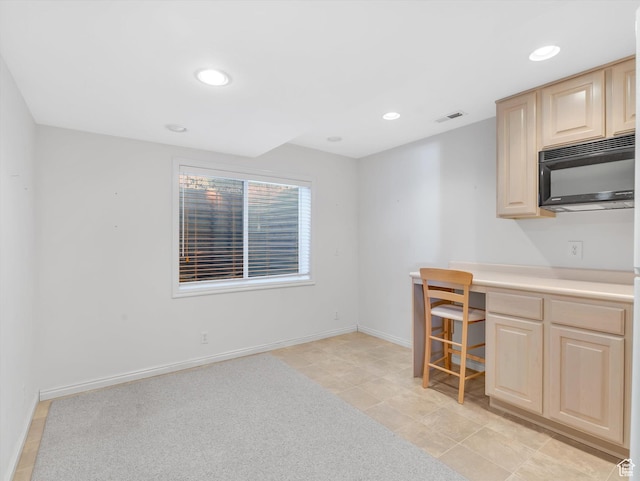 kitchen with black microwave, light brown cabinets, visible vents, and built in study area