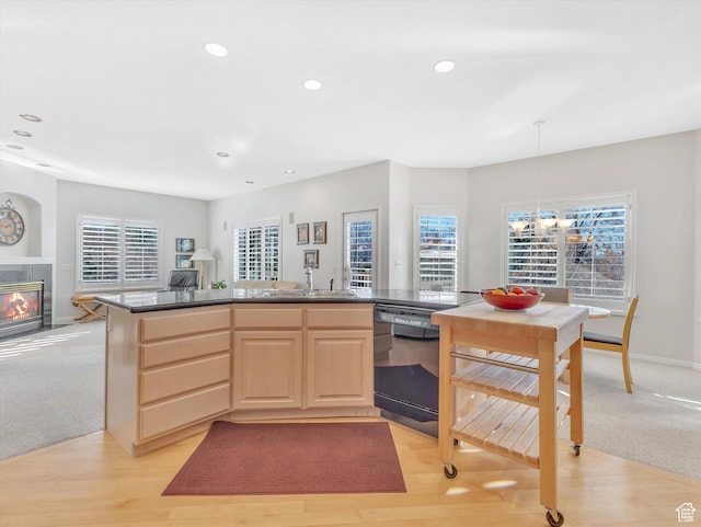 kitchen featuring open floor plan, a wealth of natural light, dishwasher, light brown cabinetry, and a tiled fireplace