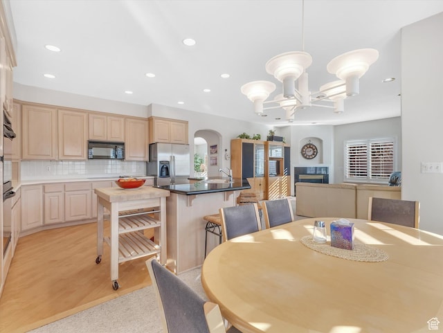 dining space with light wood finished floors, arched walkways, a fireplace, a notable chandelier, and recessed lighting