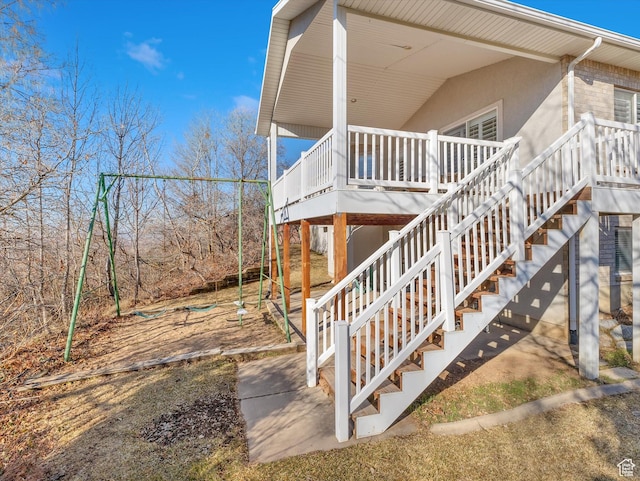 view of property exterior with a deck, brick siding, stairs, and stucco siding