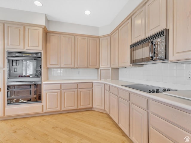 kitchen with light wood-type flooring, black appliances, light brown cabinets, and light countertops