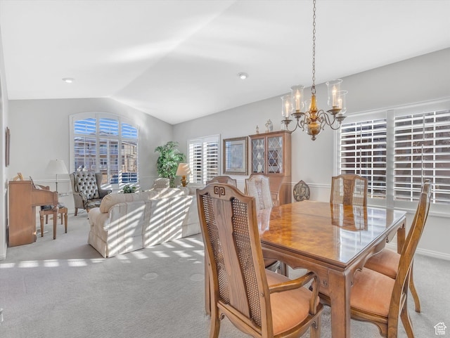 dining room with carpet floors, a chandelier, and vaulted ceiling