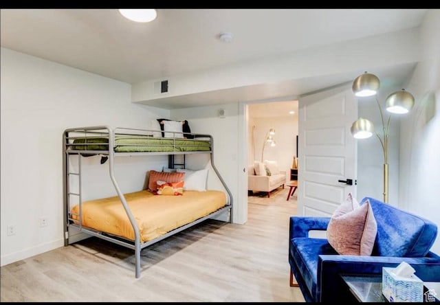 bedroom with baseboards, visible vents, and light wood finished floors