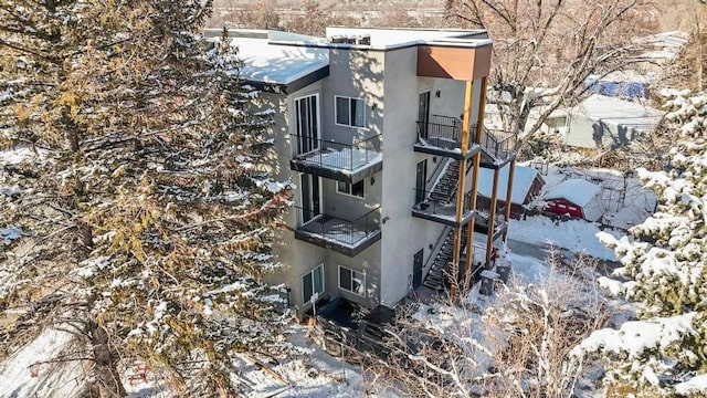 view of snow covered exterior with stairs and stucco siding