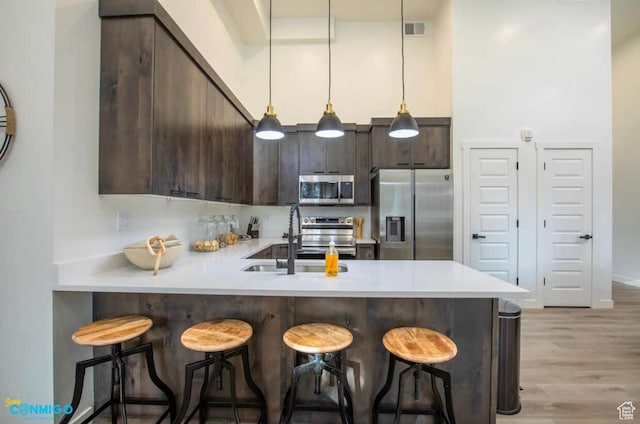 kitchen with light countertops, visible vents, appliances with stainless steel finishes, dark brown cabinetry, and a sink