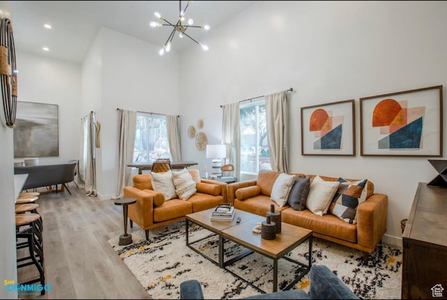 living room with a chandelier, high vaulted ceiling, baseboards, and light wood-style floors