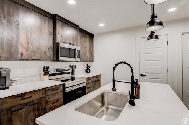 kitchen featuring appliances with stainless steel finishes, dark brown cabinets, a sink, and light countertops