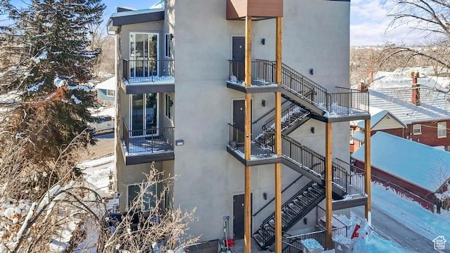 view of snowy exterior featuring stucco siding and stairs
