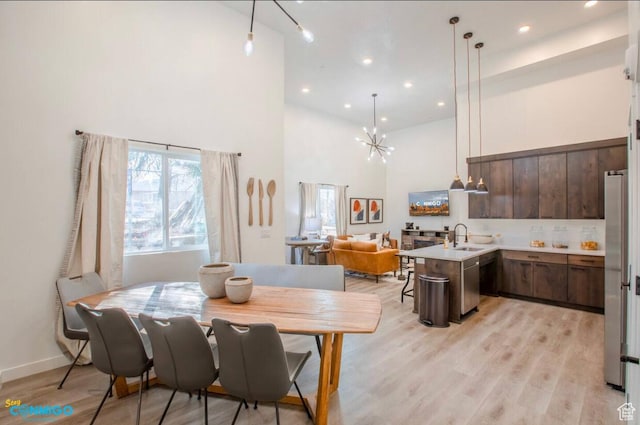 dining room featuring baseboards, a towering ceiling, light wood-type flooring, a notable chandelier, and recessed lighting