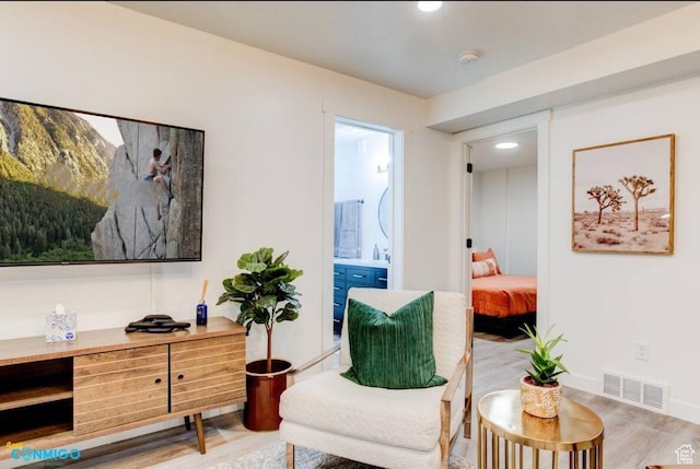 living area featuring visible vents, light wood-style flooring, and baseboards