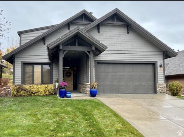 view of front facade featuring driveway, stone siding, and a front lawn