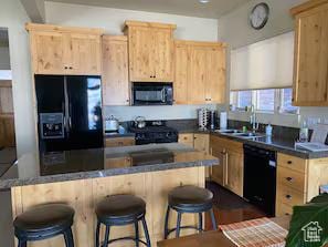 3435 Big Piney Dr, Eden, UT 84310 - kitchen with black appliances, a breakfast bar, a sink, and light brown cabinetry