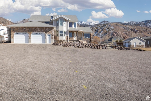 view of front of property featuring a mountain view, stone siding, and a garage