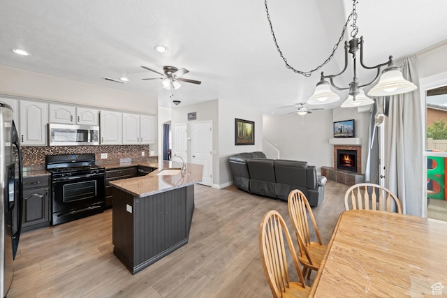 187 N Stone Mountain Dr, St George, UT 84770 - kitchen with stainless steel microwave, black gas range, a ceiling fan, white cabinets, and a sink