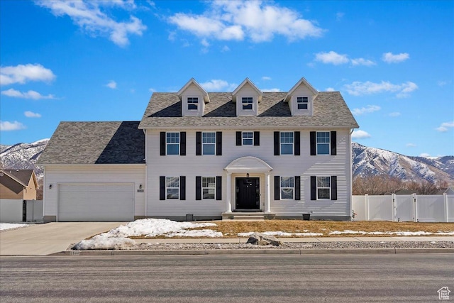 colonial inspired home featuring fence, concrete driveway, a garage, a mountain view, and a gate