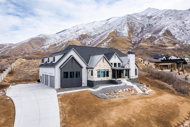 modern farmhouse featuring a chimney, a mountain view, and concrete driveway