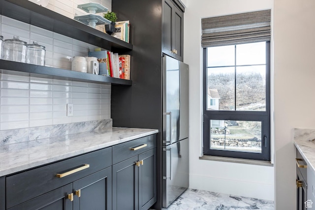 kitchen featuring marble finish floor, light stone counters, open shelves, and freestanding refrigerator