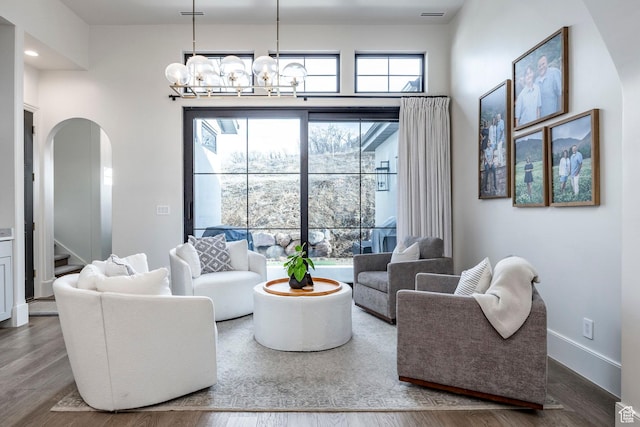 living room with arched walkways, visible vents, stairway, wood finished floors, and baseboards