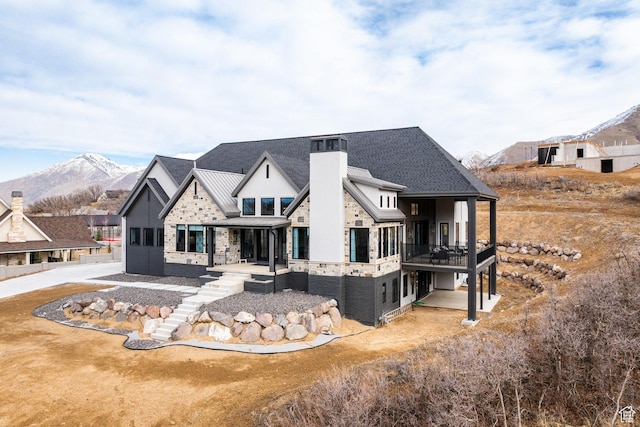 view of front of home featuring stairway, stone siding, a mountain view, and a chimney