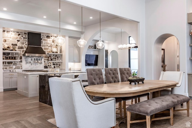 dining room featuring light wood-style floors, arched walkways, and recessed lighting