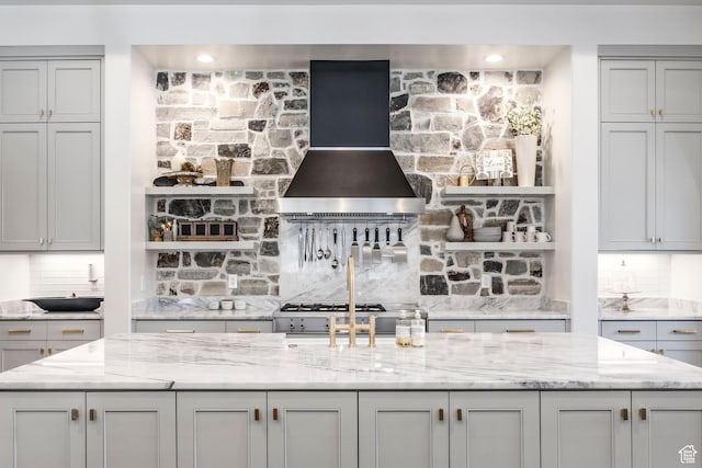 kitchen featuring light stone countertops, wall chimney range hood, tasteful backsplash, and range