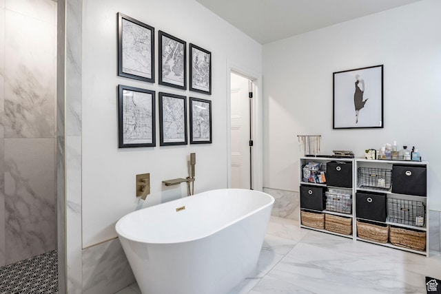 bathroom featuring marble finish floor and a soaking tub
