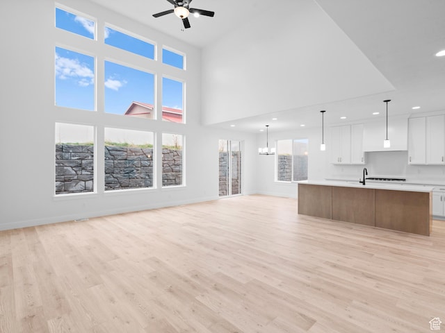 1171 W 800 S Unit 38, Spanish Fork, UT 84660 - unfurnished living room featuring baseboards, light wood-style flooring, ceiling fan with notable chandelier, and recessed lighting
