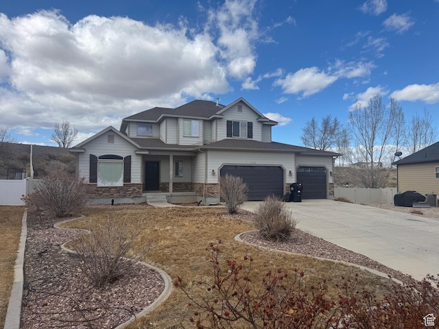 view of front of home featuring driveway, stone siding, an attached garage, and fence