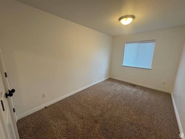 carpeted empty room with a textured ceiling and baseboards