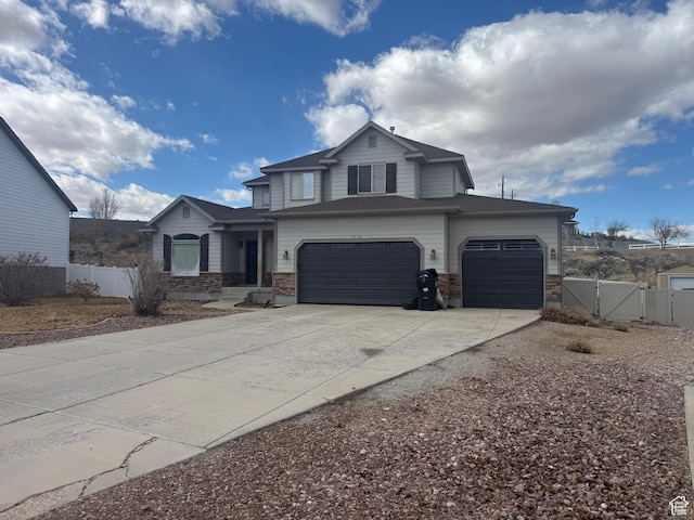 view of front of home featuring driveway, stone siding, fence, and a gate